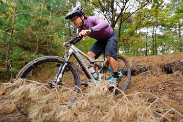 Man mountainbiket over een bospad.