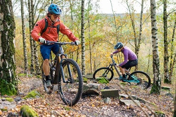 Twee fietsers mountainbiken over een bospad in de herfst.