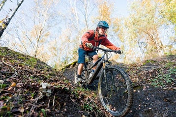 Mountainbiker rijdt bergafwaarts op een bospad.