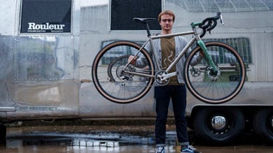 Person holding a bike in front of a silver trailer with Rouleur branding