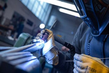 Person welding metal with protective gear in a workshop