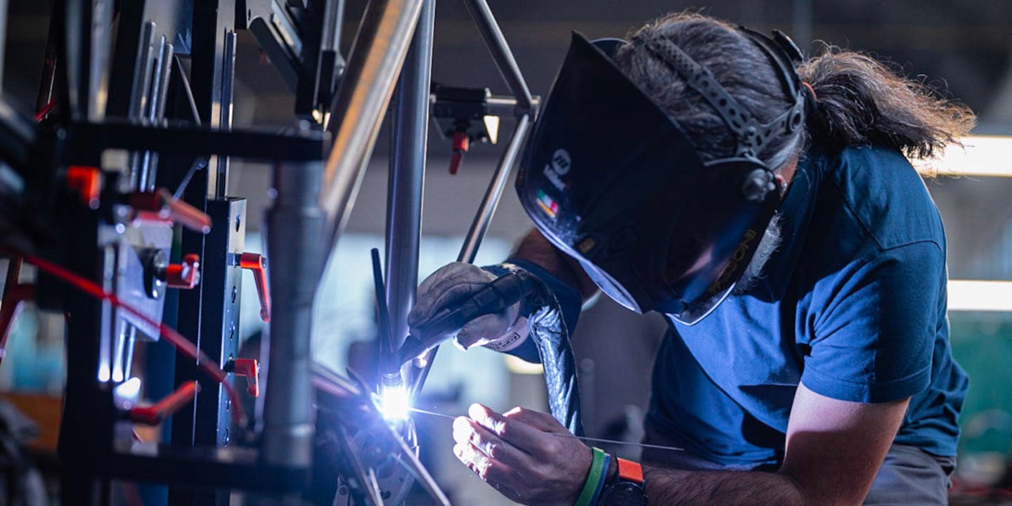 Man welding metal in a workshop with protective gear and helmet