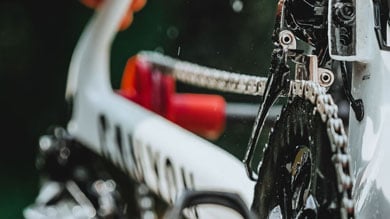 Close-up van een hand die een fiets kettingblad aanpast.