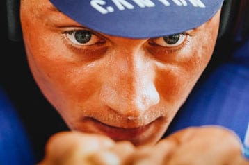 Close-up van een gefocuste wielrenner met een blauwe helm.