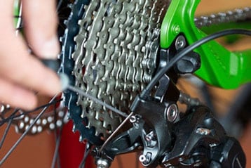 Nahaufnahme einer Hand, die ein Fahrradteil einschraubt.