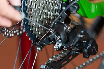 Nahaufnahme einer Hand, die ein Fahrradteil einschraubt.