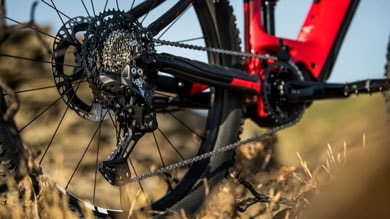 Close-up of red mountain bike gear and chain area against a blurred outdoor background