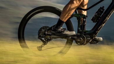 Cyclist on a mountain bike riding through grass with motion blur on the wheels