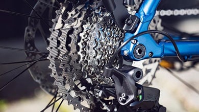 Gros plan d'un engrenage de vélo et d'un dérailleur sur un cadre bleu.