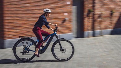 Personne roulant à vélo avec un casque dans une rue pavée.