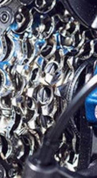 Gros plan d'une cassette de vélo et d'un dérailleur en bleu.