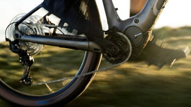 Close-up of a cyclist pedaling an electric bike on a grassy terrain