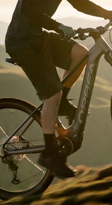 Cyclist riding a mountain bike on a trail with a scenic mountain backdrop