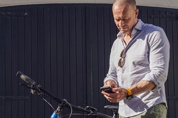 Man standing by a blue bicycle, looking at his phone.