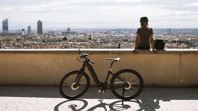 Person with a bicycle overlooking a cityscape from a high vantage point