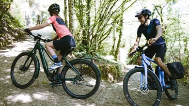 Two cyclists riding mountain bikes on a forest trail