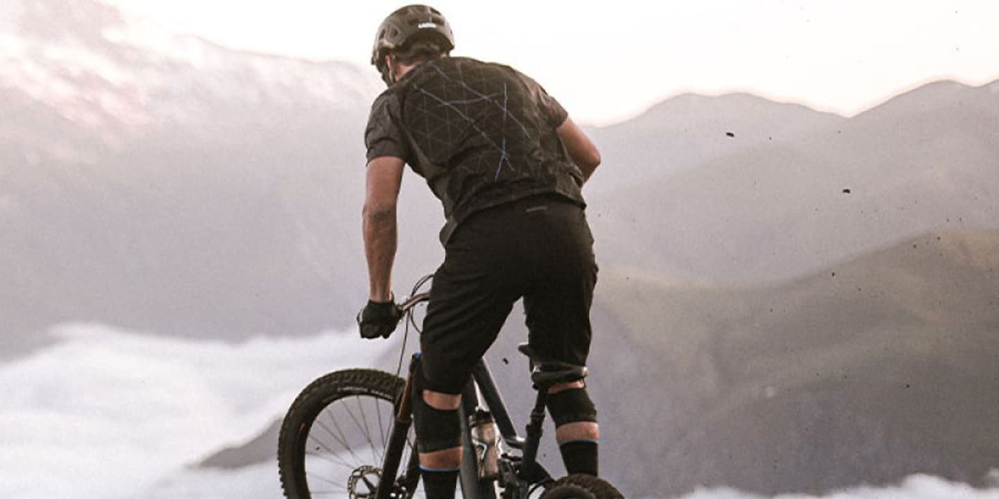 Mountain biker overlooking a foggy valley and distant snow-capped mountains