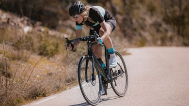 Cyclist in black gear riding on a road bike in a rural area