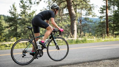 Cyclist riding on a road through a forested area