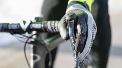 Close-up of a gloved hand gripping a Shimano bicycle brake handle