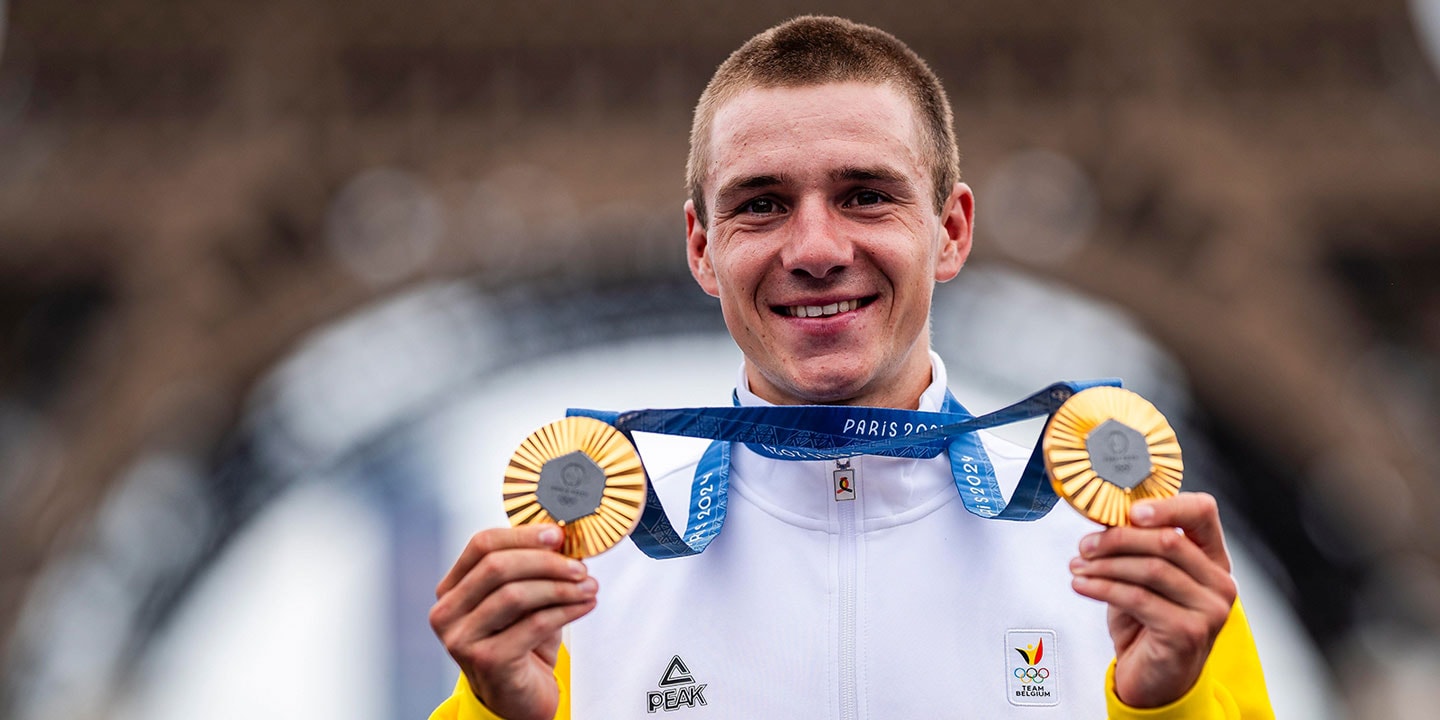 Atleta a segurar duas medalhas e a sorrir, com a Torre Eiffel no fundo