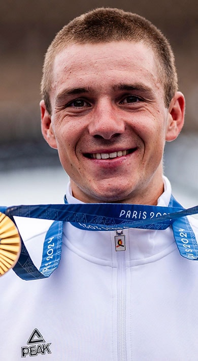 Athlete holding two medals while smiling, with the Eiffel Tower in the background