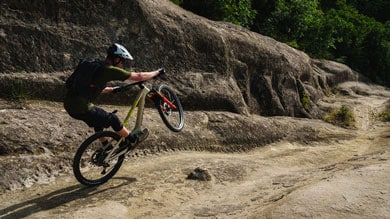 Mountain biker performing a wheelie on rocky terrain