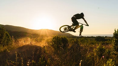 A cyclist jumping with a mountain bike against a sunset backdrop.