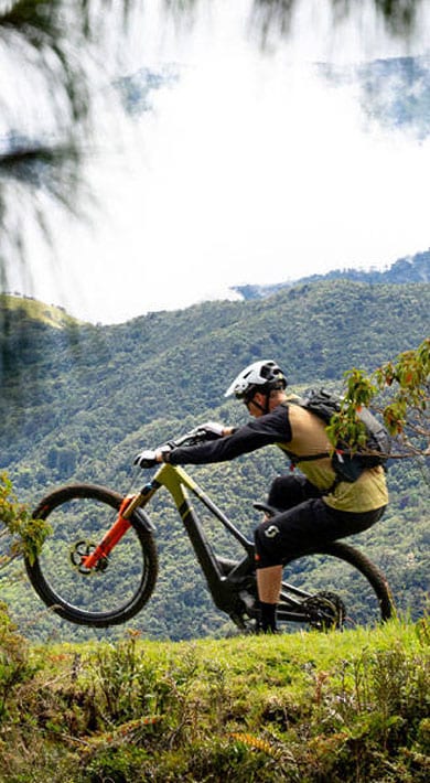 Mountain biker riding on a trail with lush green hills in the background