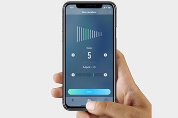 Hand holding a smartphone displaying bike gear adjustment app screen