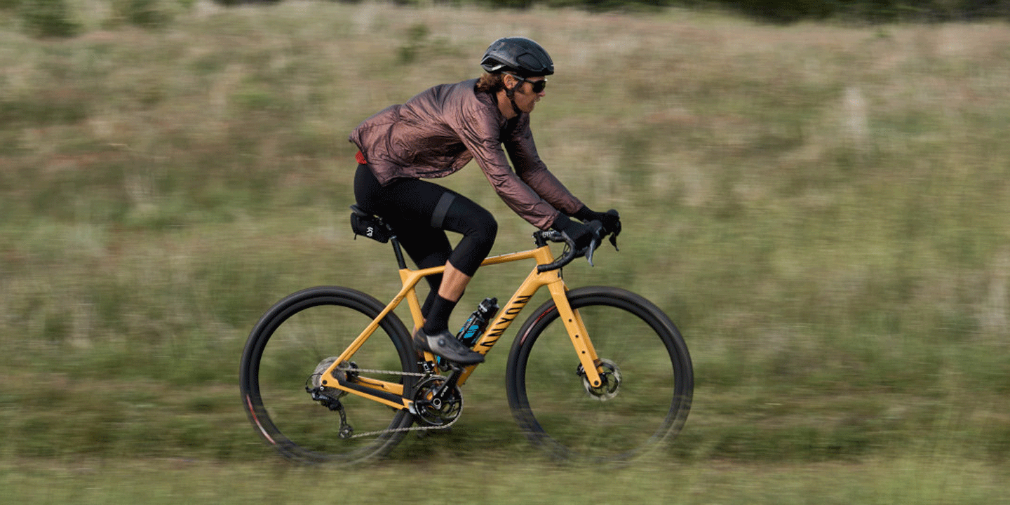 Cyclist riding an orange Canyon bike in a grassy field