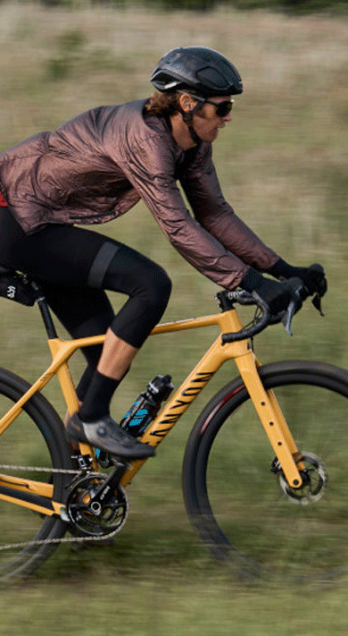 Cyclist riding an orange Canyon bike in a grassy field