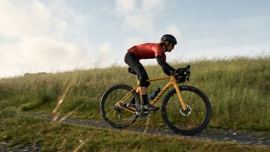 Cyclist in red jersey riding through grassy field