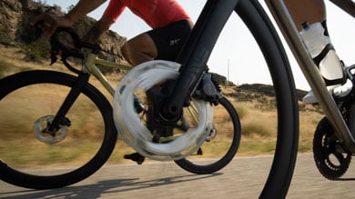 Close-up of two cyclists riding on a road, focusing on the bicycle wheels.