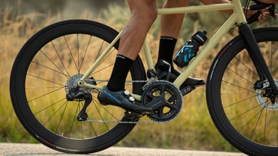 Cyclist pedaling a beige road bike on an outdoor path