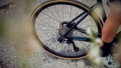 Rear wheel and drivetrain of a Scott bicycle with a cyclist's leg and shoe visible