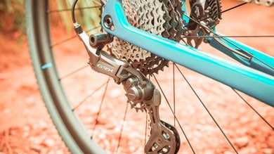 Close-up of a Shimano GRX derailleur on a blue bicycle, showing the rear gear cassette