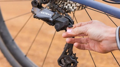 Hand adjusting a Shimano GRX rear derailleur on a bicycle