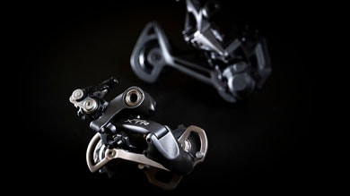 Two bicycle derailleurs on a dark background.