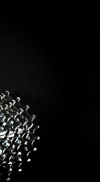 Bicycle cassette and derailleur on black background.