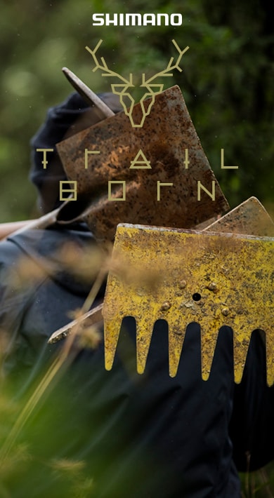 Personne portant un outil de jardinage sur l'épaule, entourée de verdure