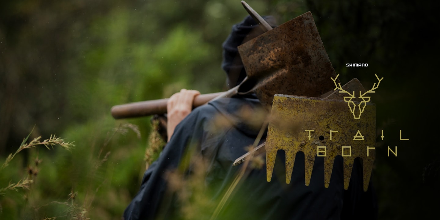 Person carrying a gardening tool over their shoulder surrounded by greenery