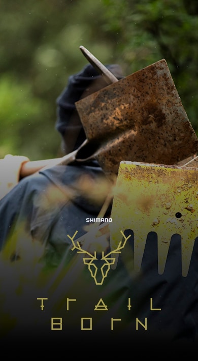 Person carrying a gardening tool over their shoulder surrounded by greenery