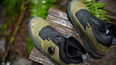 Pair of waterproof hiking boots on a wooden surface surrounded by greenery