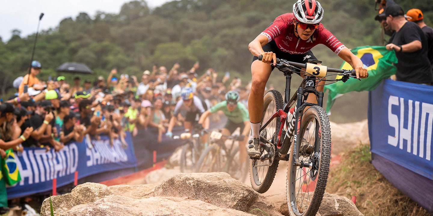 Mountain bike racer riding over rocks in front of cheering crowd