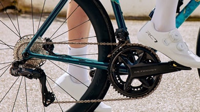 Close-up of a bike drivetrain and cyclist wearing white shoes and socks