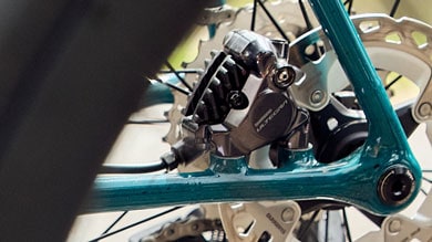 Close-up of Shimano Ultegra bicycle disc brake caliper on a teal bike frame