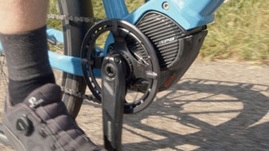 Fahrradpedal und Schuh in Bewegung auf einem sonnigen Weg.