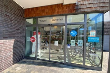 Glastür-Eingang zu einem Geschäft mit den Schildern „Verkauf“ und „Werkstatt“.