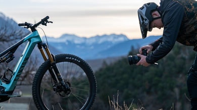 Person fotografiert ein Fahrrad mit Bergen im Hintergrund